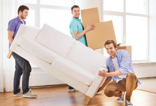 Removal team planning a flat move in Ilford with boxes and furniture in a shared hallway